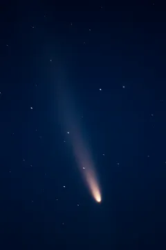 Widok komety na nocnym niebie z widocznym jasnym ogonem gwiezdnym