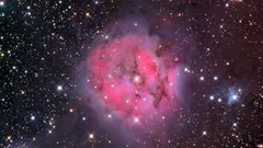 Mgławica w kosmosie, różowa chmura gazu i pyłu otoczona gwiazdami na tle nocnego nieba.